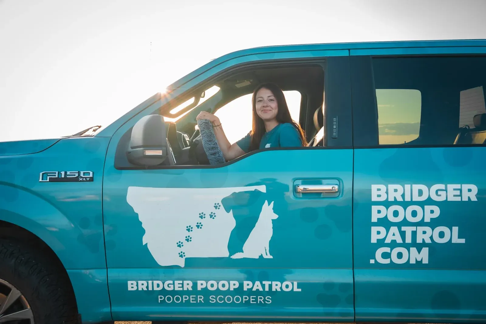 Angelina in the driver's seat of the teal Bridger Poop Patrol truck